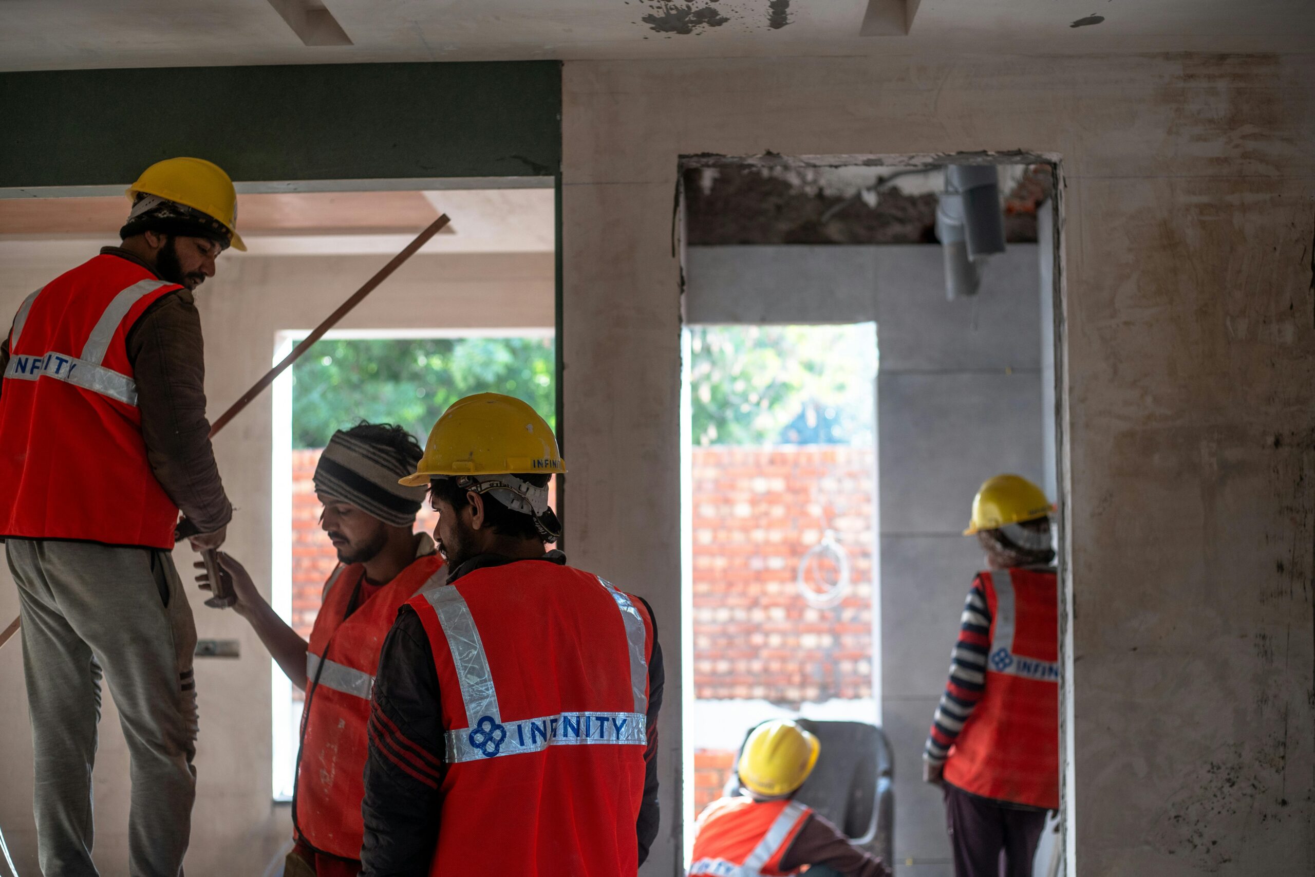Construction workers wearing safety gear at an indoor building site in Delhi.